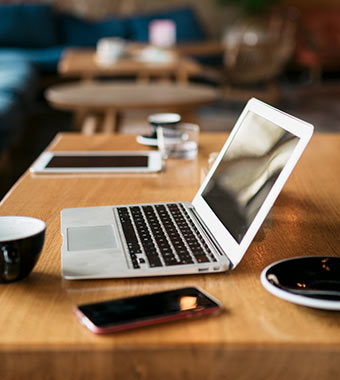 open laptop with coffee, tablet, and mobile phone nearby