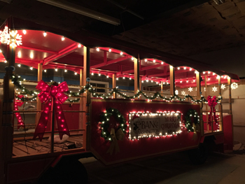 Red trolley decorated with lights and wreaths for Holiday parade