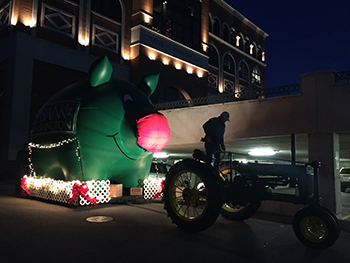 Bank of Washington employee driving a tractor pulling the big inflatable pig dressed as Rudolph for the 2015 Holiday Parade of Lights
