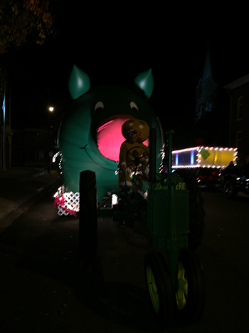 Bank of Washington employees dressed as Gingerbread Man driving a tractor pulling the big inflatable pig dressed as Rudolph for the 2015 Holiday Parade of Lights