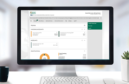 Desktop computer displaying Bank of Washington digital banking homepage with succulent, keyboard, and black coffee cup