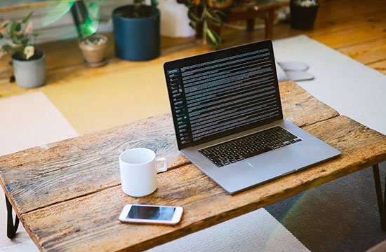 open laptop with coffee mug and mobile phone nearby