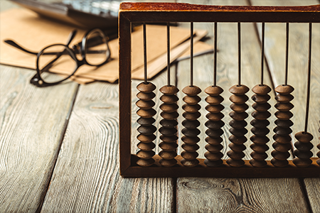 abacus sitting on wooden table with a pair of glasses and paper on desk behind it