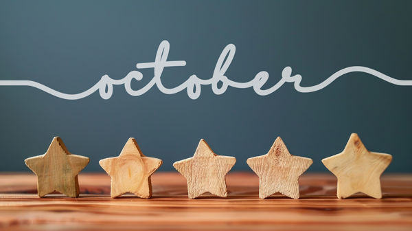 five wooden stars on a wood table with a navy background and the word "October" written in cursive above 