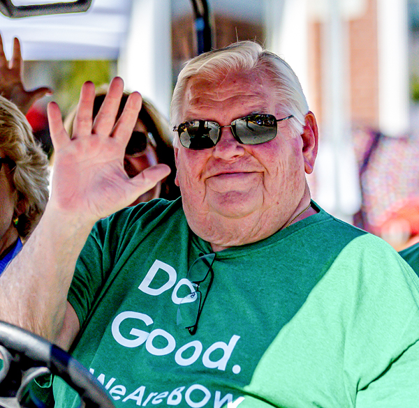 Image of L.B. Eckelkamp Jr. waving to the camera and smiling while wearing Bank of Washington Do Good green shirt